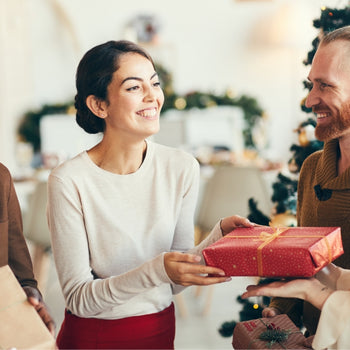 a group of individuals smile while exchanging gifts